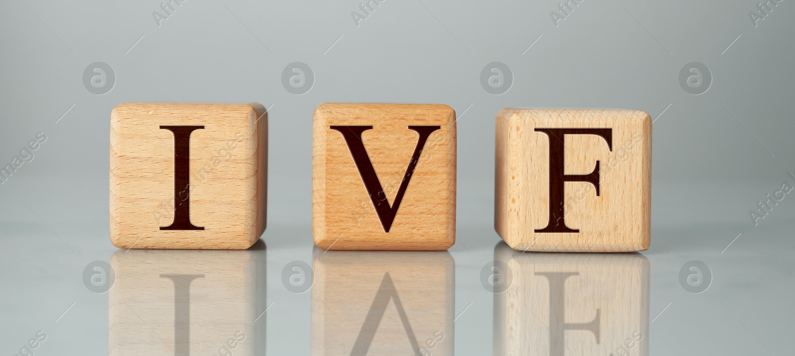 Image of In vitro fertilization. Wooden cubes with abbreviation IVF on grey background. Banner design