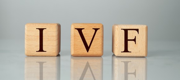 Image of In vitro fertilization. Wooden cubes with abbreviation IVF on grey background. Banner design