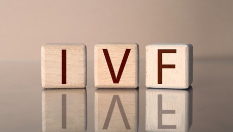 Image of In vitro fertilization. Wooden cubes with abbreviation IVF on pale brown background. Banner design