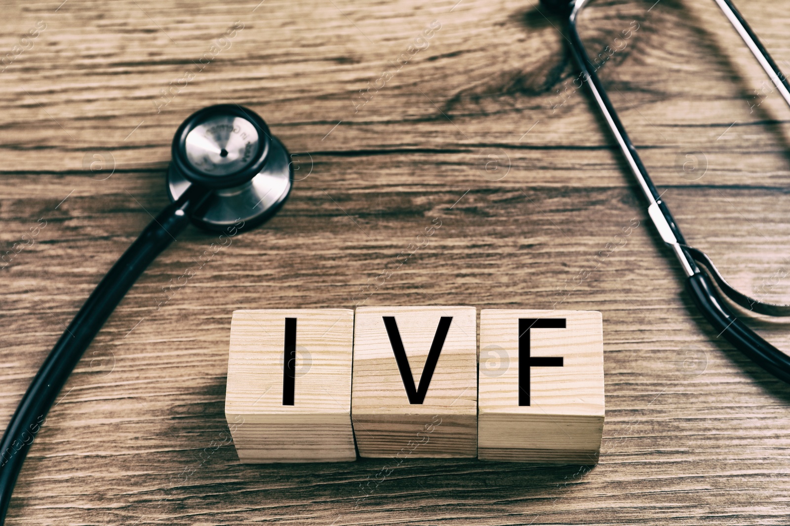 Image of In vitro fertilization. Wooden cubes with abbreviation IVF and stethoscope on wooden table
