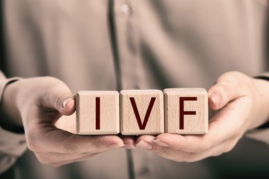 Image of In vitro fertilization. Woman holding wooden cubes with abbreviation IVF, closeup