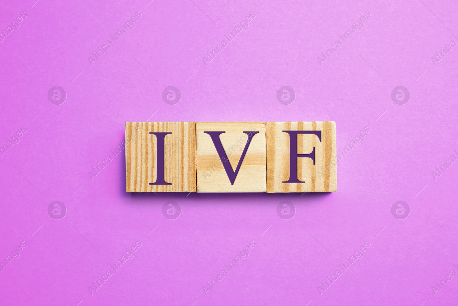 Image of In vitro fertilization. Wooden cubes with abbreviation IVF on violet background, top view