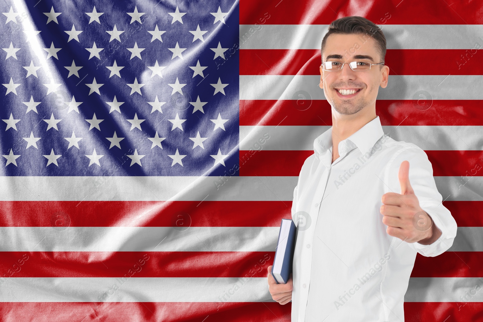 Image of Student or teacher with book showing thumbs-up against flag of USA. Language school