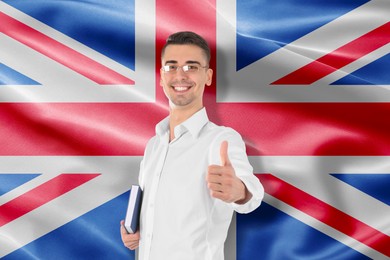 Image of Student or teacher with book showing thumbs-up against flag of United Kingdom. Language school