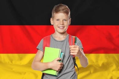Image of Little boy with backpack and stationery against flag of Germany. Language school