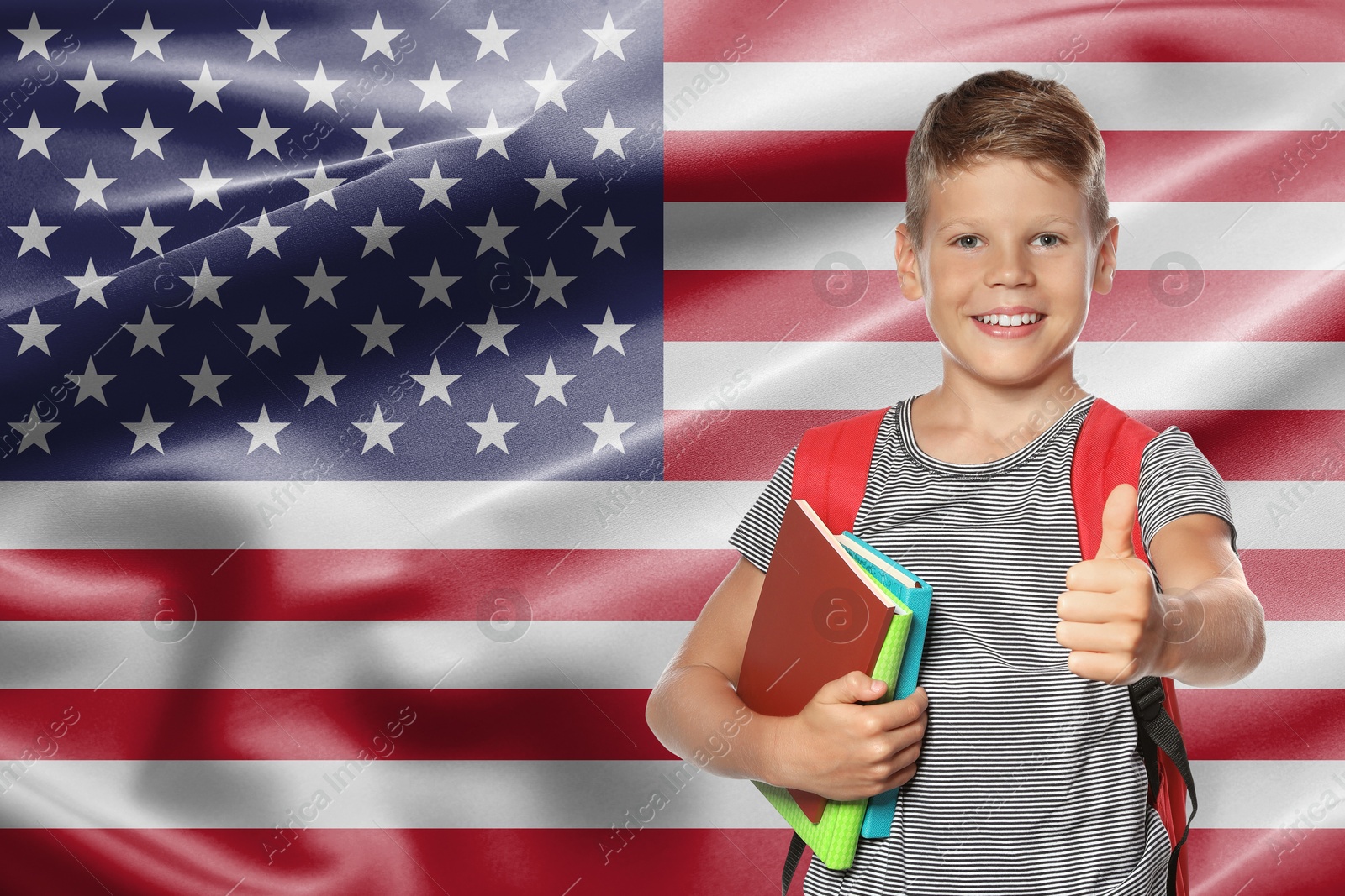 Image of Little boy with backpack and stationery showing thumbs-up against flag of USA. Language school