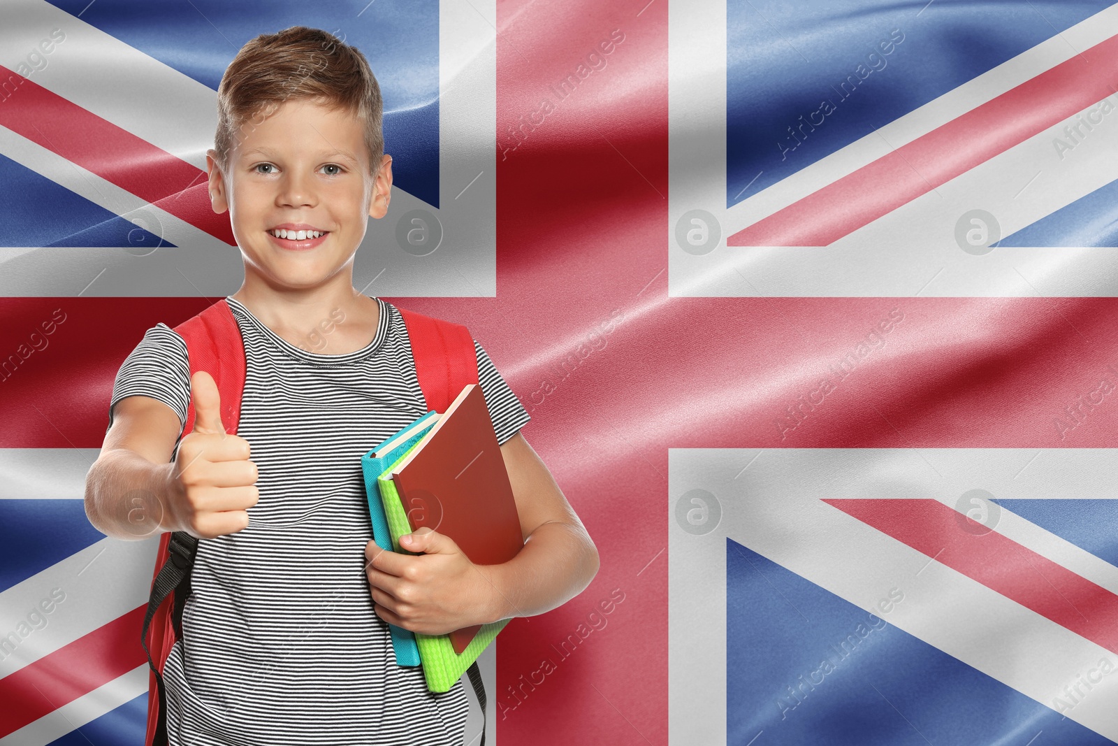 Image of Little boy with backpack and stationery showing thumbs-up against flag of United Kingdom. Language school