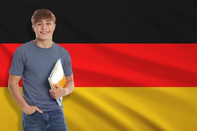 Image of Happy student with notebooks against flag of Germany. Language school