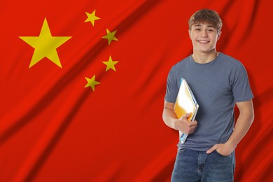 Image of Happy student with notebooks against flag of China. Language school