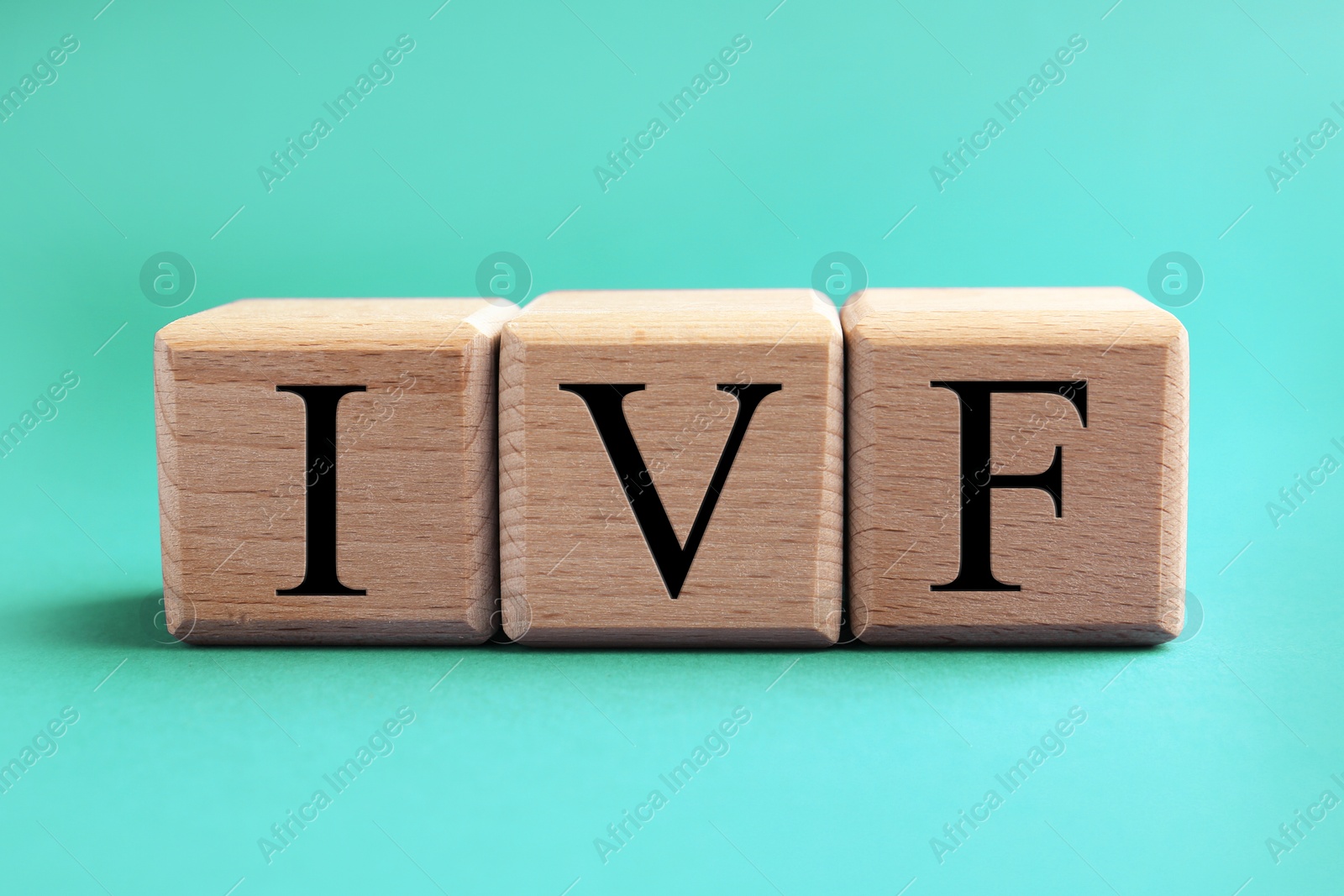 Image of In vitro fertilization. Wooden cubes with abbreviation IVF on turquoise background