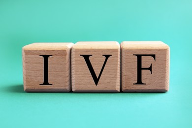 Image of In vitro fertilization. Wooden cubes with abbreviation IVF on turquoise background