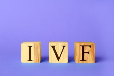 Image of In vitro fertilization. Wooden cubes with abbreviation IVF on violet blue background