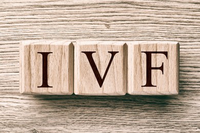 Image of In vitro fertilization. Cubes with abbreviation IVF on wooden background, top view
