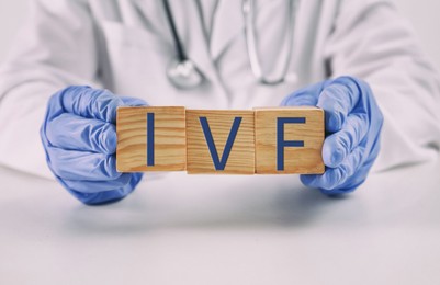 Image of In vitro fertilization. Doctor holding wooden cubes with abbreviation IVF above table, closeup