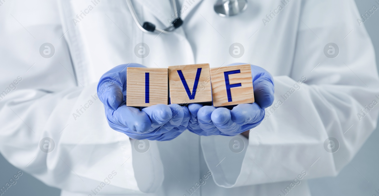 Image of In vitro fertilization. Doctor holding wooden cubes with abbreviation IVF, closeup. Banner design