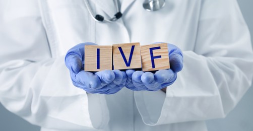 Image of In vitro fertilization. Doctor holding wooden cubes with abbreviation IVF, closeup. Banner design