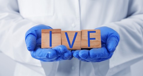 Image of In vitro fertilization. Doctor holding wooden cubes with abbreviation IVF, closeup. Banner design