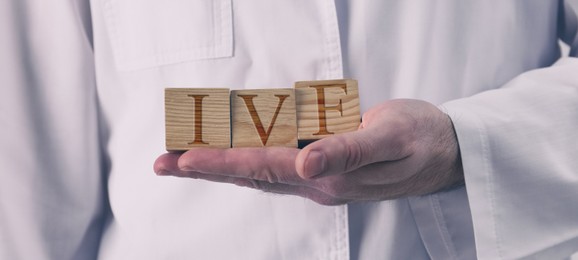 Image of In vitro fertilization. Doctor holding wooden cubes with abbreviation IVF, closeup. Banner design