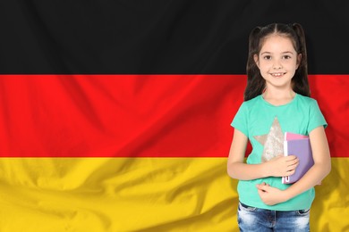 Image of Little girl with notebooks against flag of Germany. Language school