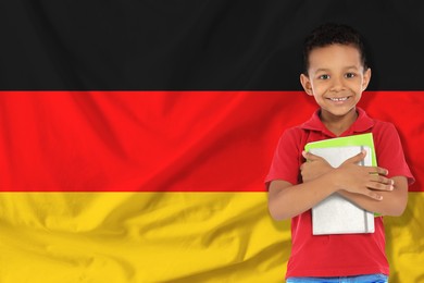 Image of Little boy with notebooks against flag of Germany. Language school