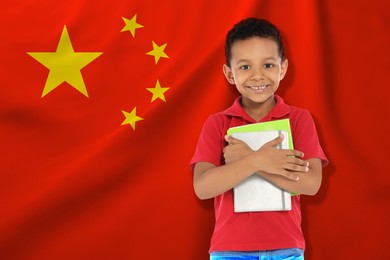 Image of Little boy with notebooks against flag of China. Language school