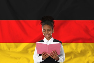 Image of Little girl with book against flag of Germany. Language school