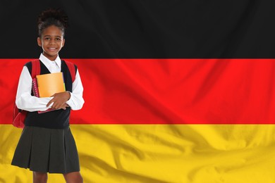 Image of Little girl with backpack and notebooks against flag of Germany. Language school