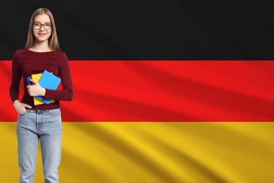 Image of Student with eyeglasses and notebooks against flag of Germany. Language school