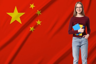 Image of Student with eyeglasses and notebooks against flag of China. Language school
