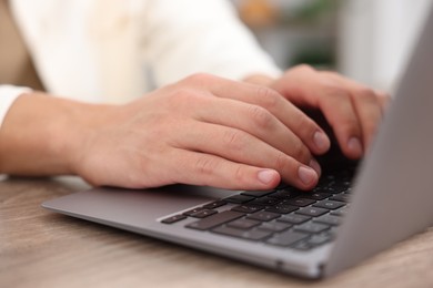 Photo of Man passing online test on laptop at wooden table indoors, closeup