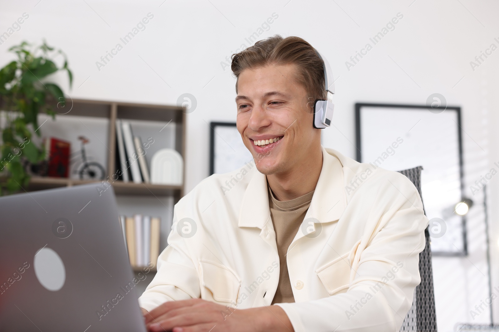 Photo of Man in headphones passing online test on laptop indoors