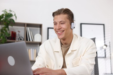 Photo of Man in headphones passing online test on laptop indoors