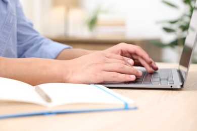 Photo of Man passing online test via laptop at table indoors, closeup