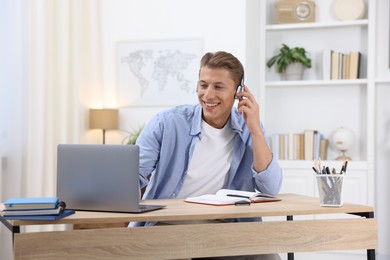 Photo of Man in headphones passing online test via laptop at table indoors