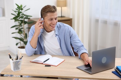 Photo of Man in headphones passing online test via laptop at table indoors