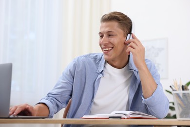 Photo of Man in headphones passing online test via laptop at table indoors