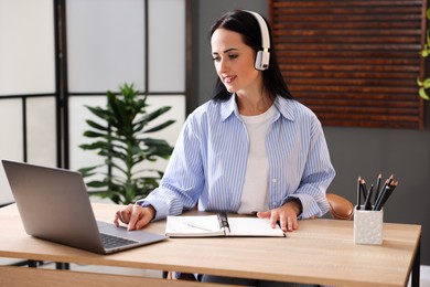 Photo of Woman passing online test via laptop at table indoors