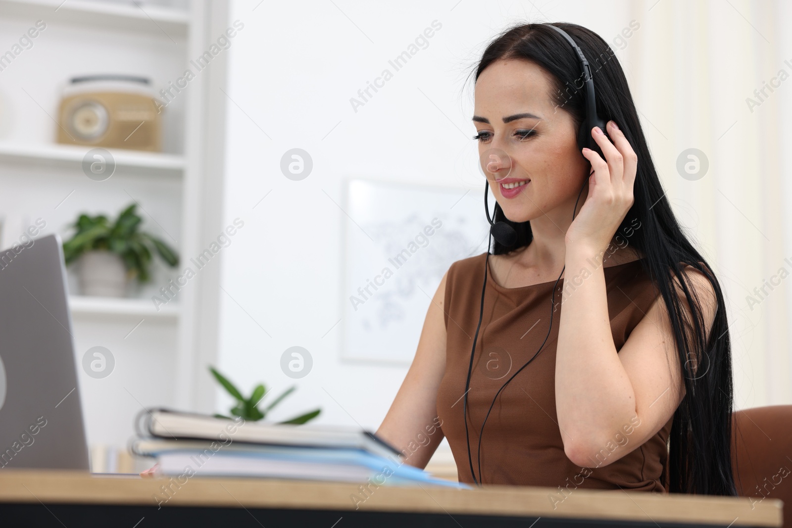 Woman in headset passing online test via laptop at table indoors Photo of Woman in headset passing online test via laptop at table indoors