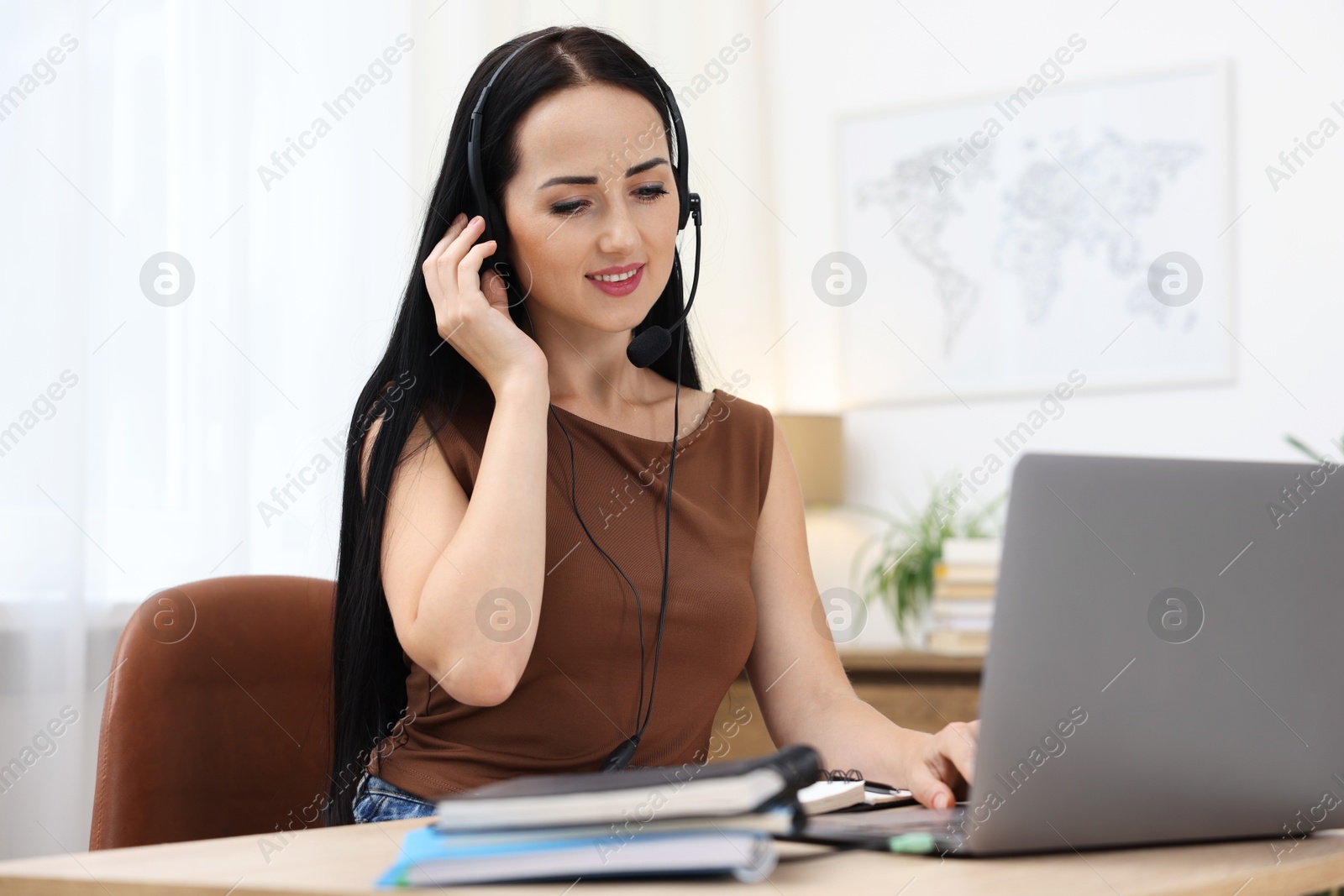 Woman in headset passing online test via laptop at table indoors Photo of Woman in headset passing online test via laptop at table indoors
