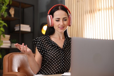 Photo of Woman in headphones passing online test via laptop indoors