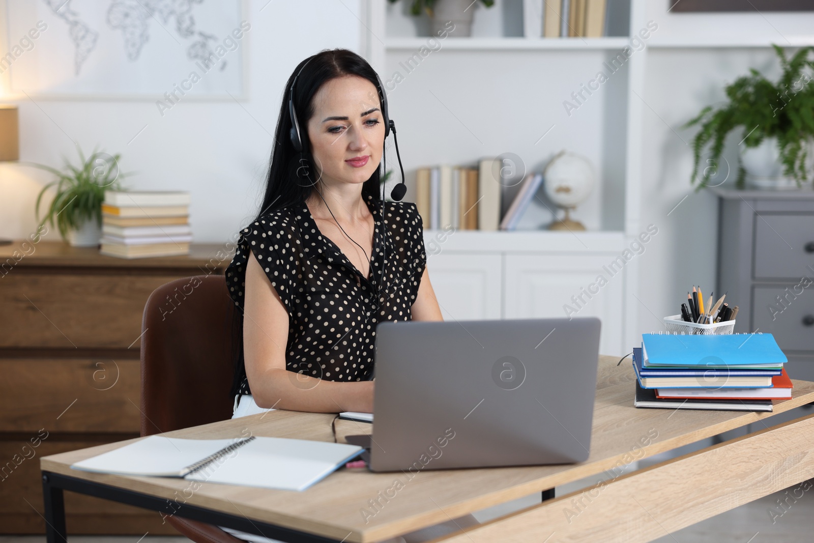 Woman in headset passing online test via laptop at table indoors Photo of Woman in headset passing online test via laptop at table indoors