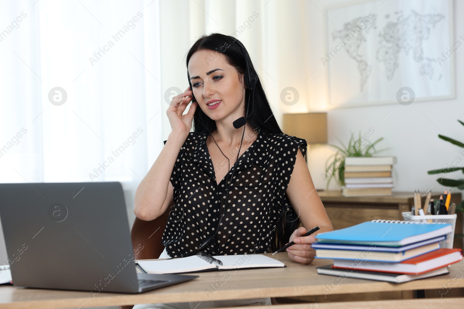 Woman in headset passing online test via laptop at table indoors Photo of Woman in headset passing online test via laptop at table indoors