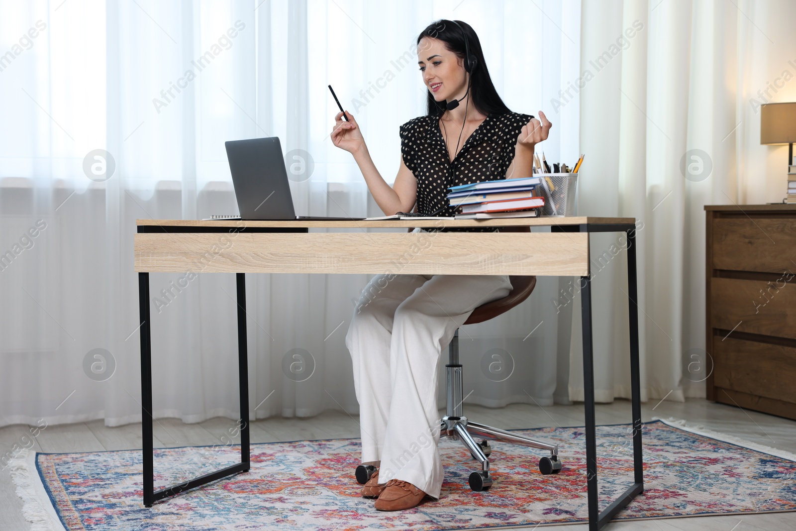 Woman in headset passing online test via laptop at table indoors Photo of Woman in headset passing online test via laptop at table indoors