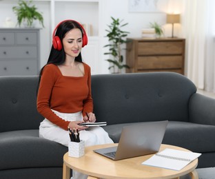 Photo of Woman taking notes while passing online test via laptop at home