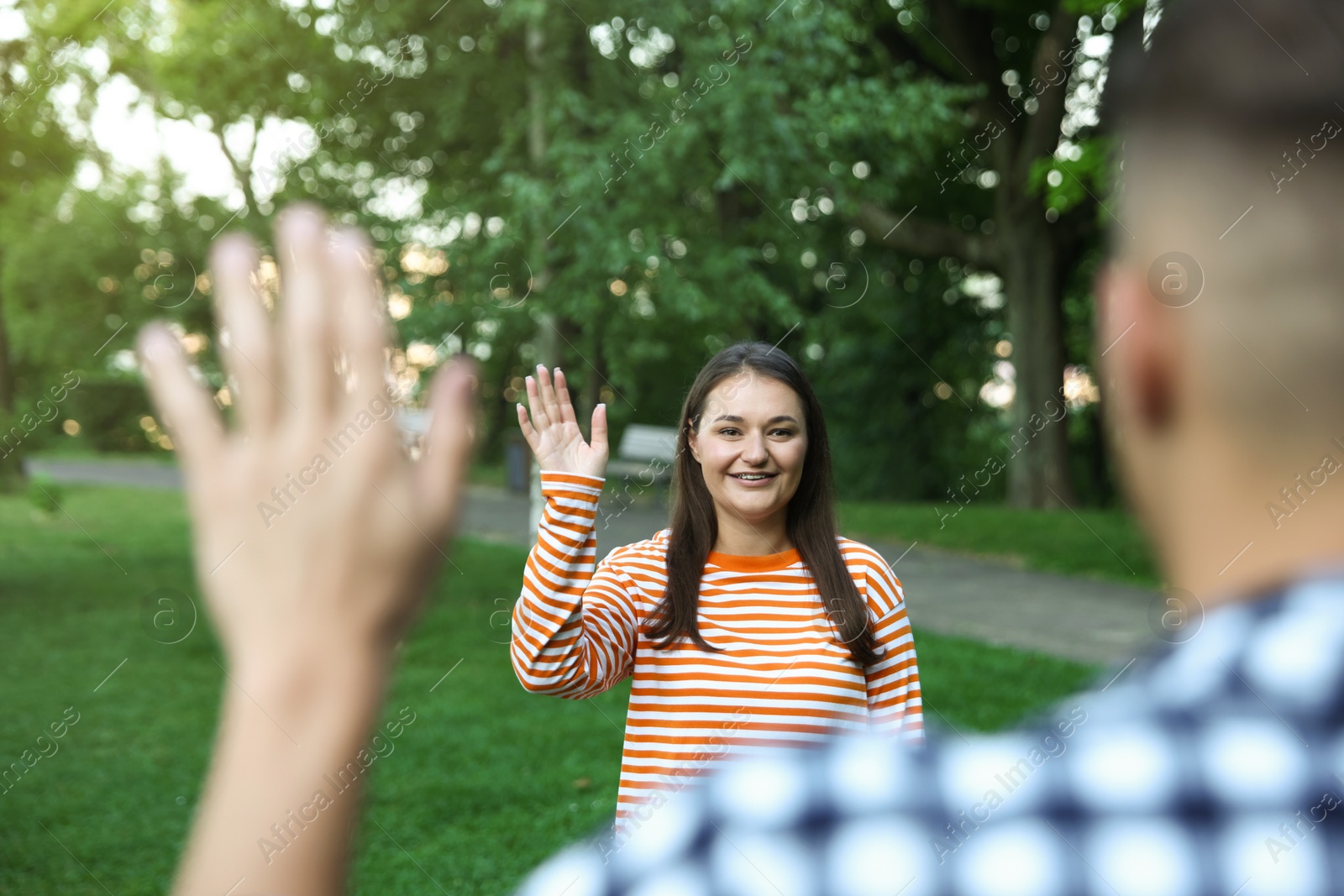 Photo of Woman waving goodbye to her friend in park, selective focus