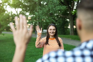 Photo of Woman waving goodbye to her friend in park, selective focus