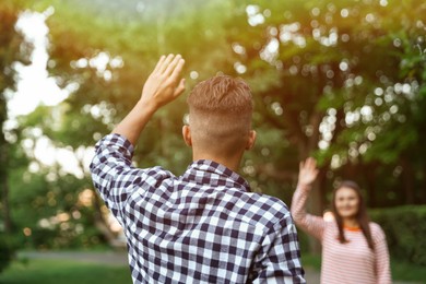 Photo of Woman waving goodbye to her friend in park, selective focus