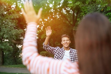 Photo of Woman waving goodbye to her friend in park, selective focus
