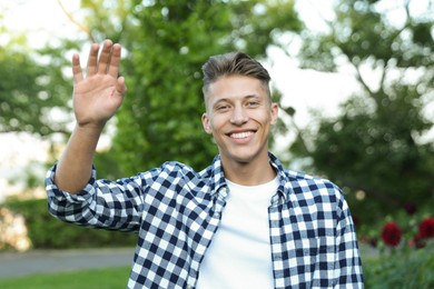 Photo of Happy young man waving goodbye in park