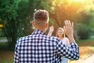 Photo of Man waving goodbye to his friend in park, selective focus